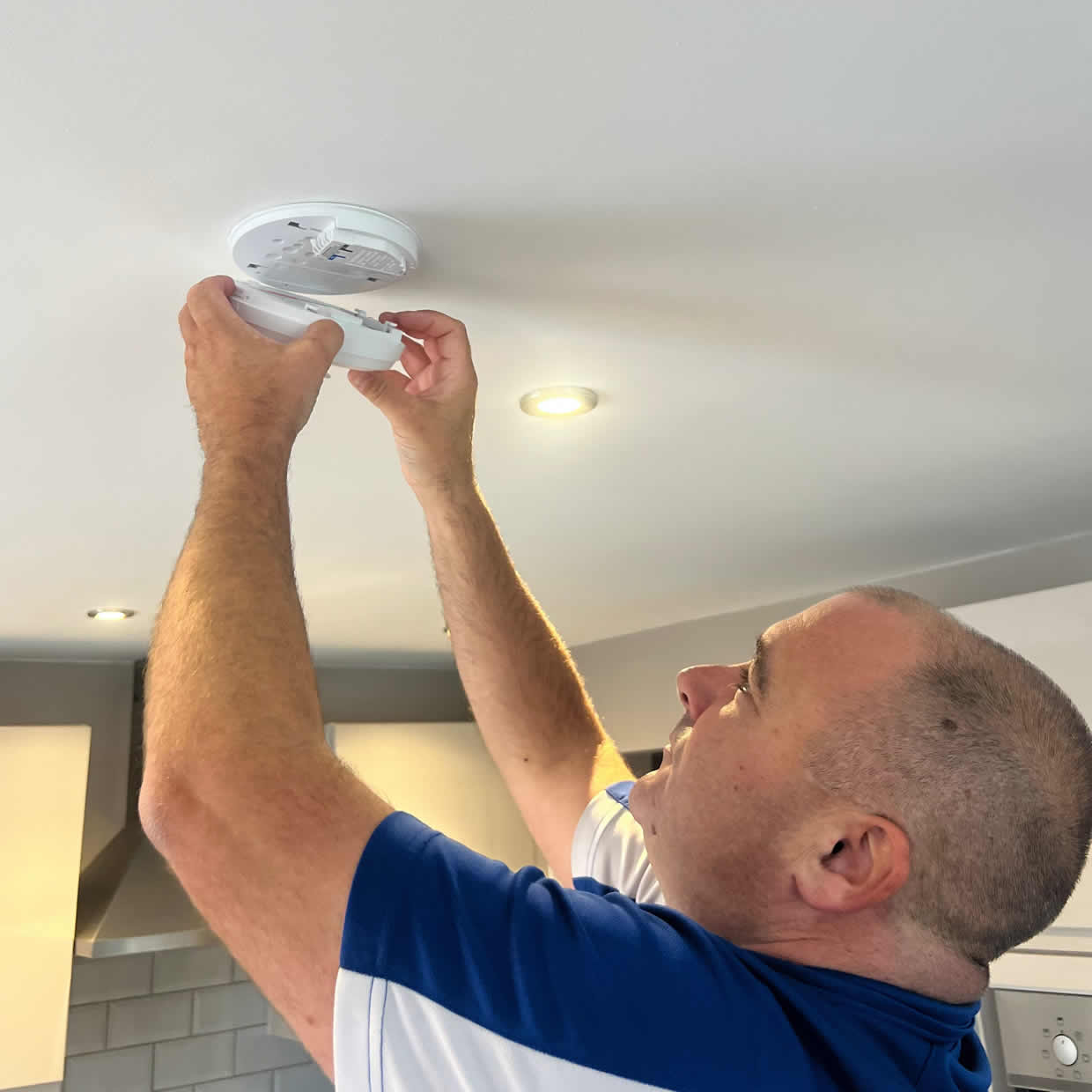 Smoke alarm installer fitting an alarm in a Weybridge property